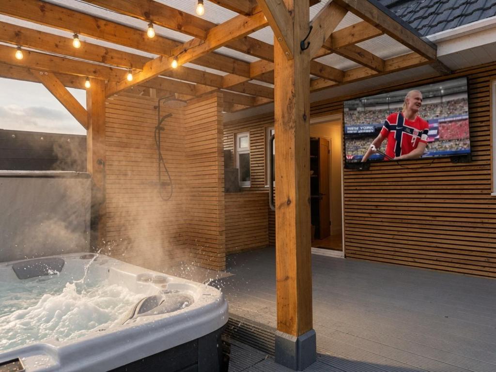 a bathroom with a tub with a tv on the wall at Nordic Spa House in Brandon