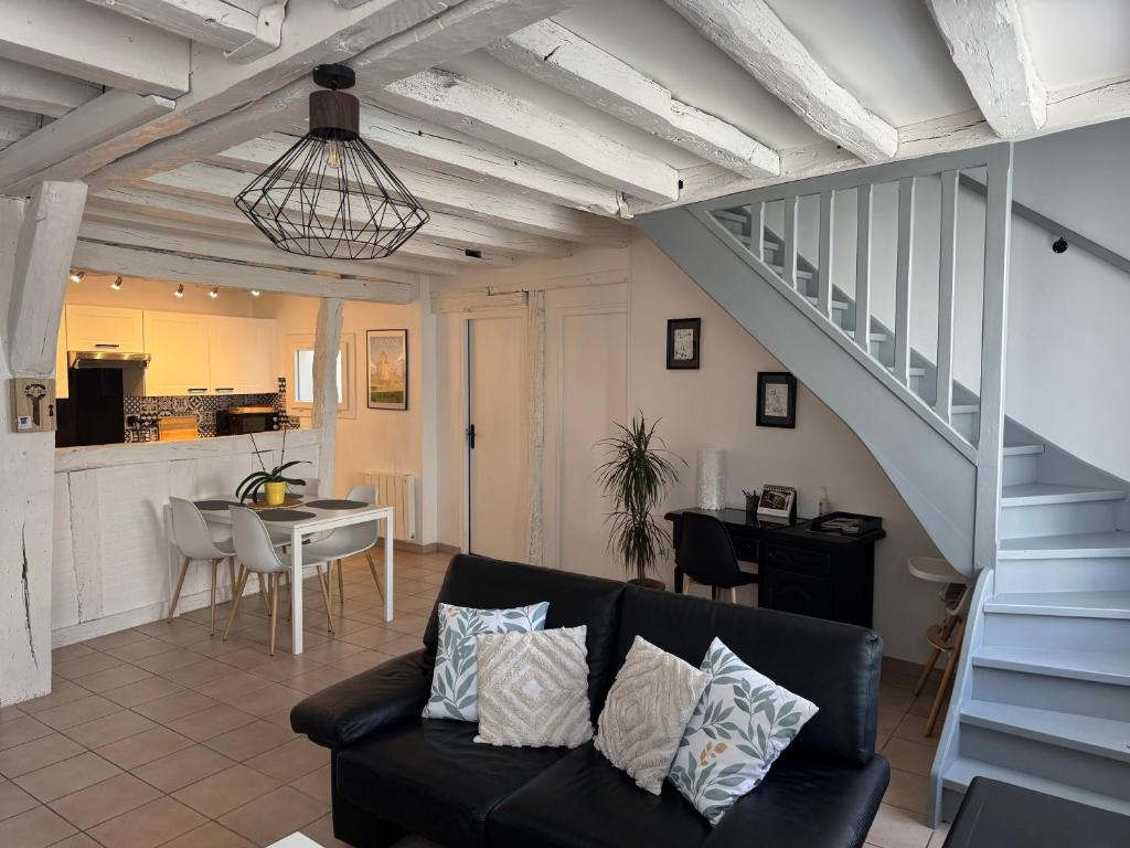 a living room with a black couch and a staircase at Le Marais Vous - Duplex en centre-ville. in Provins