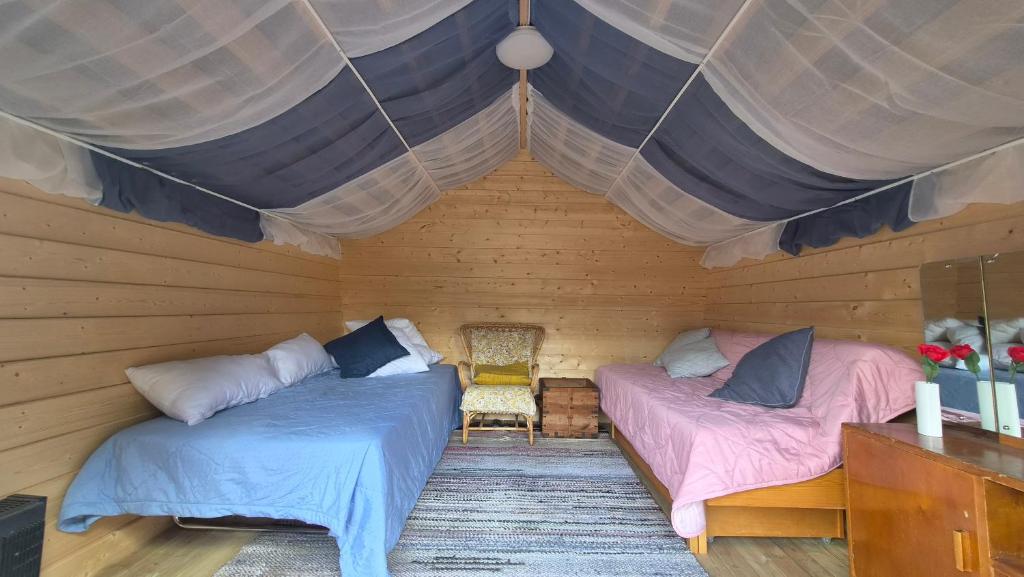 a room with two beds in a wooden house at Pikku aitta in Heikkilä