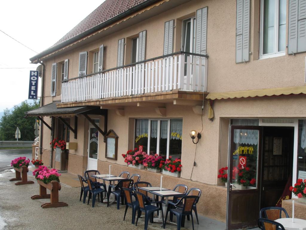 a restaurant with tables and chairs in front of a building at Hôtel Bar Restaurant de la Poste Le 1900 in Jougne