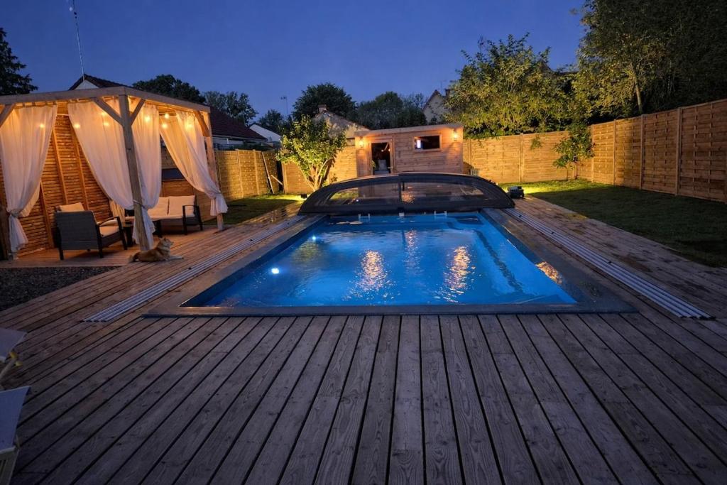 a swimming pool on a wooden deck at night at Lodge avec piscine chauffée privative et ou Studio avec son SPA, SAUNA HAMAMM privatifs in Cepoy
