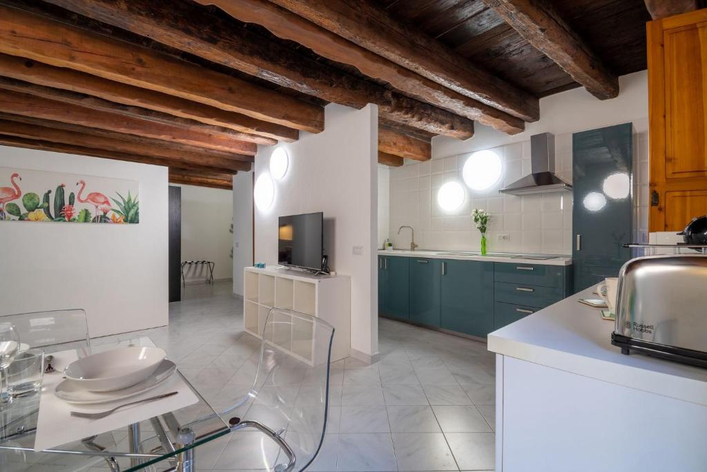 a large kitchen with blue cabinets and a tv at Sotto la torre Apartment in Cagliari