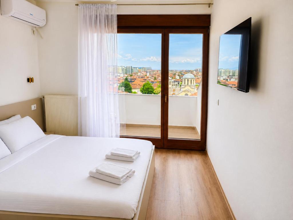 a bedroom with a white bed and a window at Makadam Hotel in Prizren