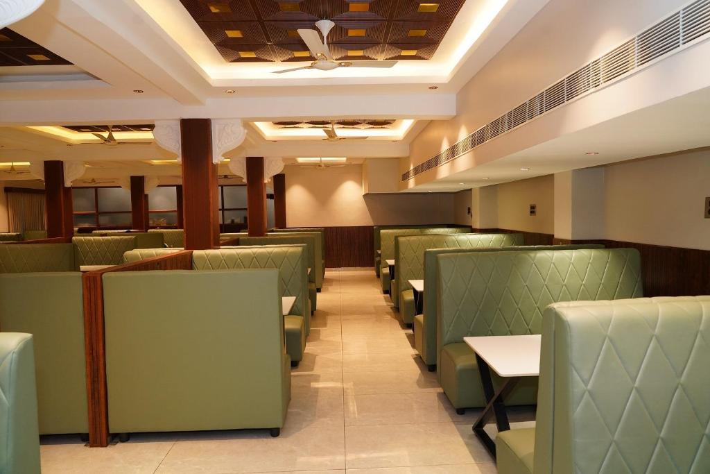 a dining room with green chairs and tables at Hotel G Grand Inn in Thanjāvūr