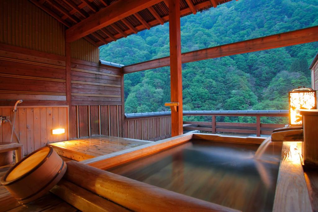 a hot tub in a wooden room with a view at Enraku in Kurobe