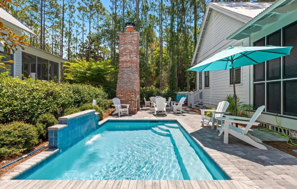 a swimming pool in a yard with a table and an umbrella at Southern Living Cottage in Santa Rosa Beach