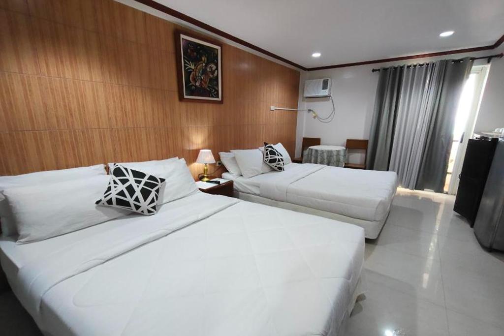 a hotel room with two beds and a couch at Shenna's Beach Resort Boracay in Boracay