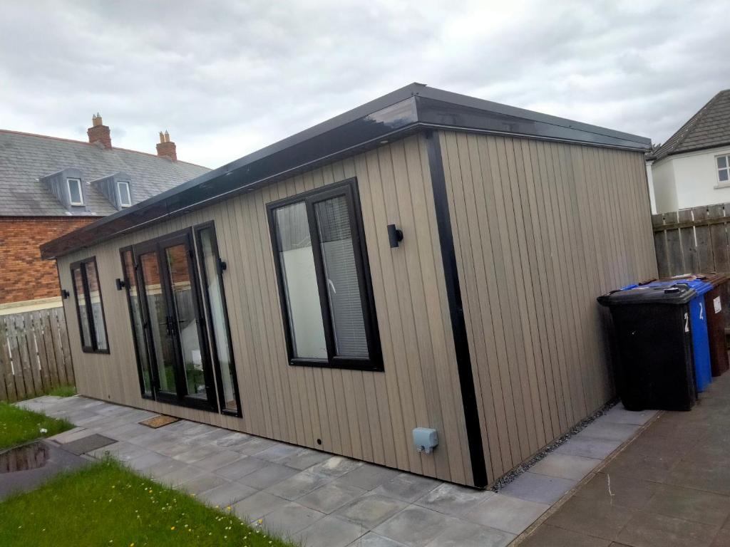 a large wooden shed with a black roof at The Place CABIN in Coleraine