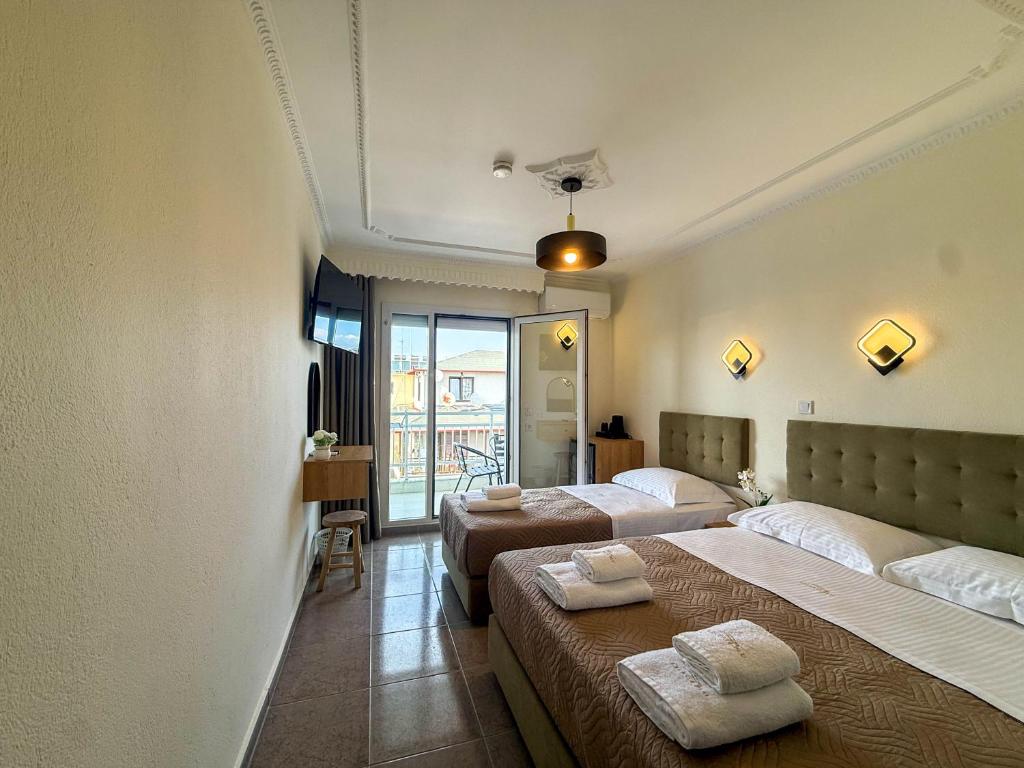 a hotel room with two beds and a balcony at Celeste Blu Suites & Rooms in Paralia Katerinis