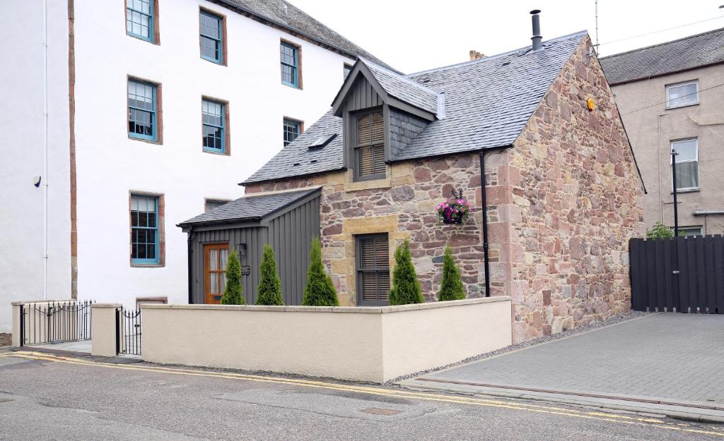 an old stone building with a black roof at Balnain Street Cottage in Inverness