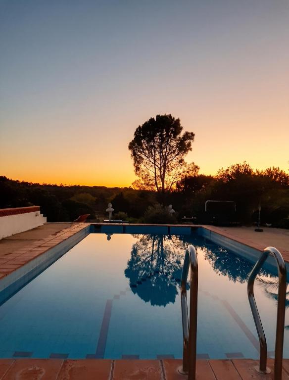 a swimming pool with a sunset in the background at Comfortable Studio in Santiago do Cacém, private pool, 65 m² in Santiago do Cacém