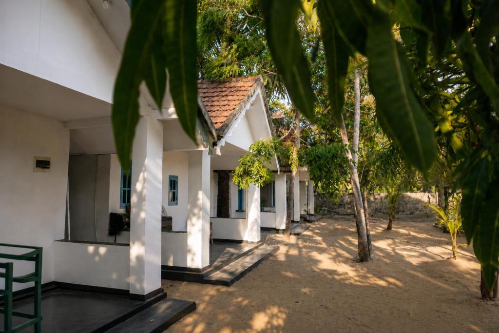 a white building with trees in front of it at Zen Yoga & Surf House in Arugam Bay