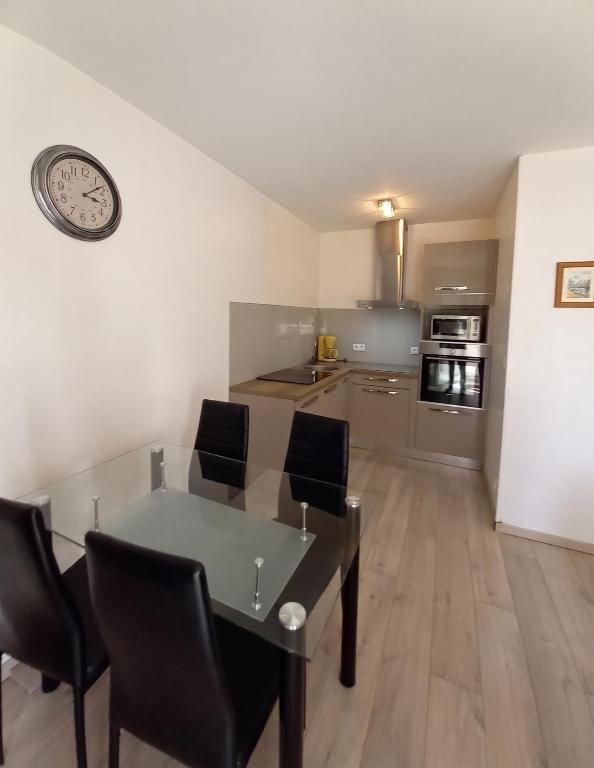 a kitchen with a table and chairs and a clock on the wall at Appartement charmant à Chambéry de 35 m² + balcon privatif in Chambéry