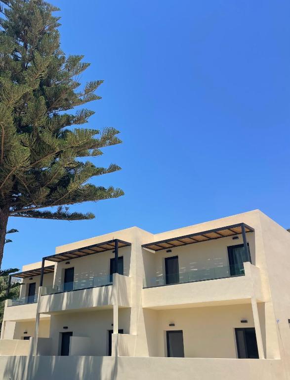 a building with a tree in front of it at Nikos Apartments & Studios in Plakias