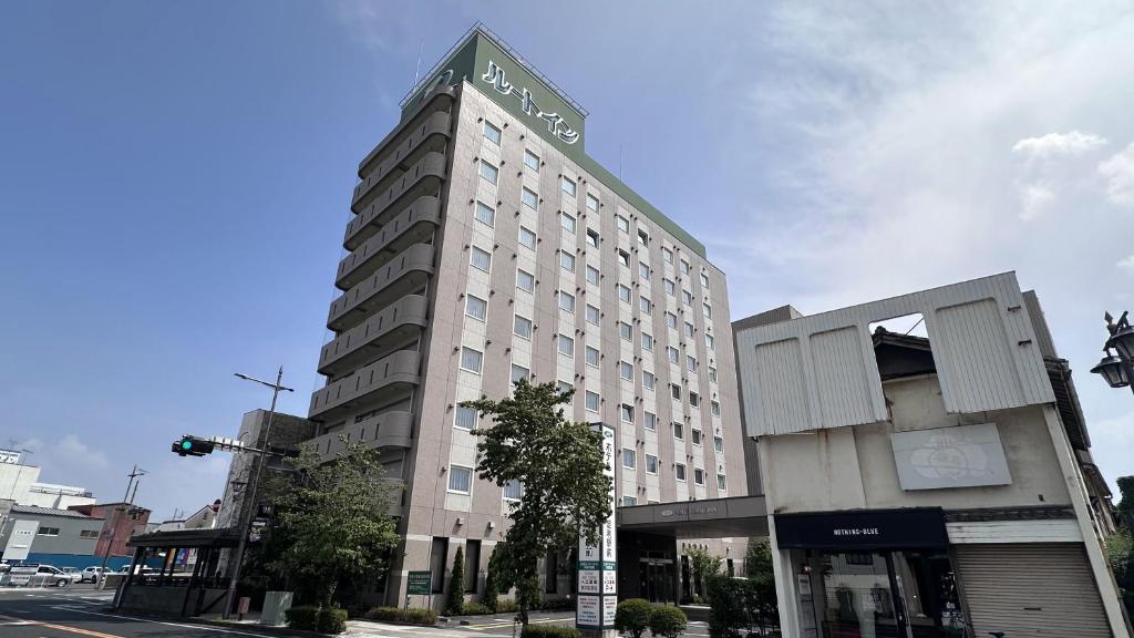 a tall white building on a city street at Hotel Route-Inn Ashikaga Ekimae in Ashikaga