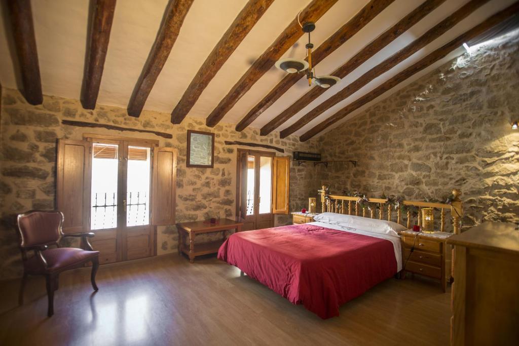 a bedroom with a red bed and a stone wall at Casa rural la Posada ,Terra Alta, Matarraña. in Caseras