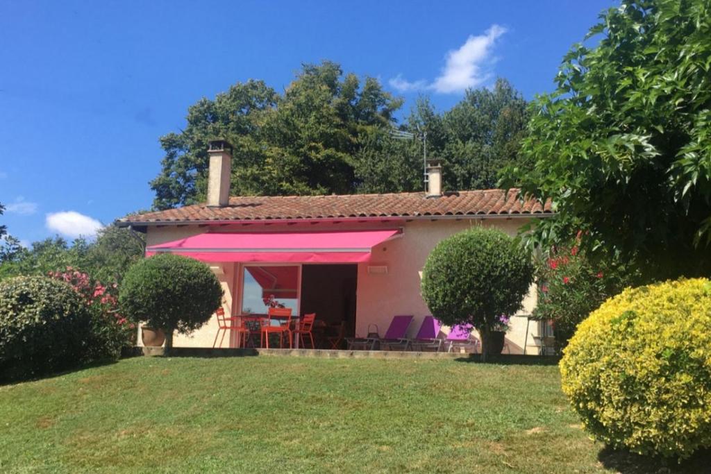 a small white house with a pink awning at Maison au charme champêtre - Monlaur-Bernet in Monlaur-Bernet