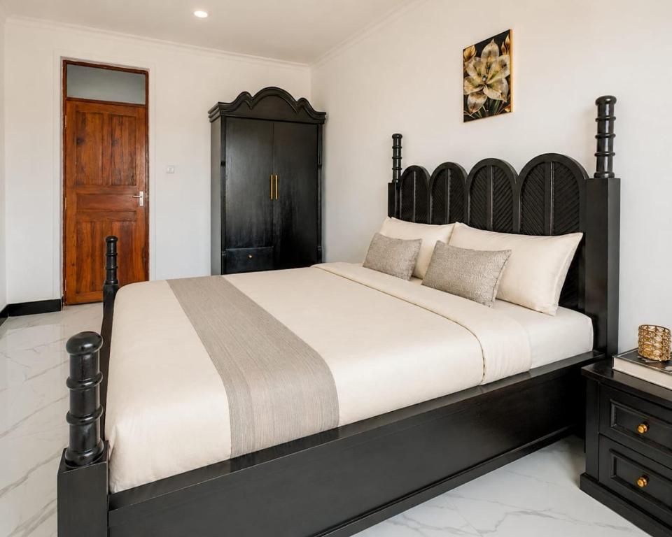 a bedroom with a large bed with a wooden headboard at City Getaway Apartment in Zanzibar City