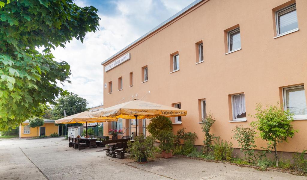 a building with tables and umbrellas in front of it at Pension Küfner in Markkleeberg