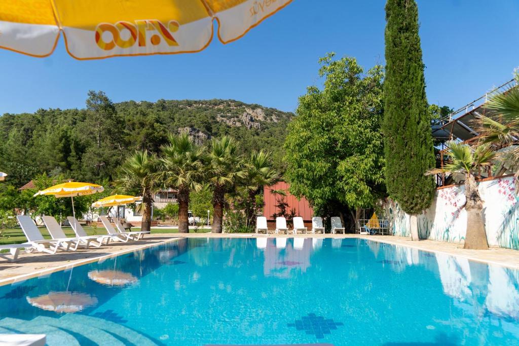 a swimming pool with chairs and umbrellas at a resort at Olympos Donkisot Pansiyon in Antalya