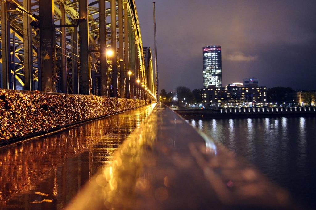 eine Brücke über das Wasser bei Nacht mit Gebäuden in der Unterkunft Hostel Cologne in Köln