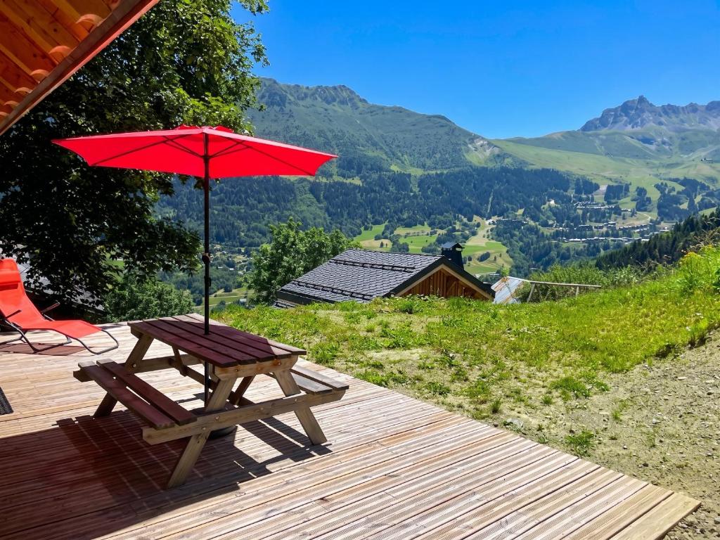 a wooden deck with a picnic table and an umbrella at Chalet accueillant avec vue sur la montagne - 180 m² - Valmorel in Les Avanchers