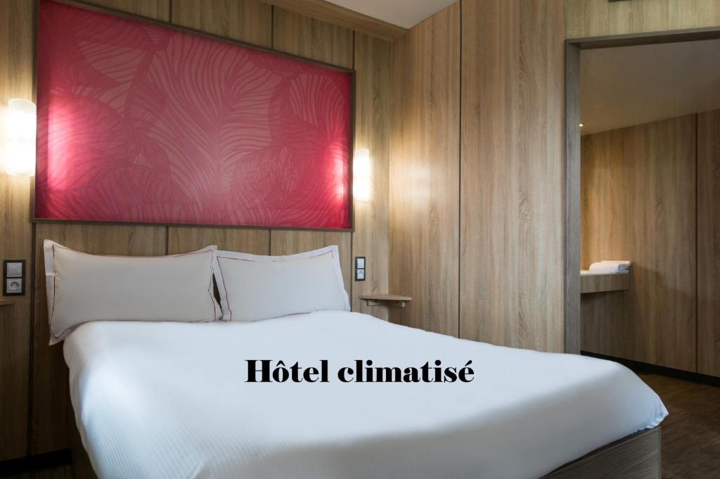 a large white bed in a room with a red wall at The Originals Access Aéroport, Hôtel Aurillac in Aurillac