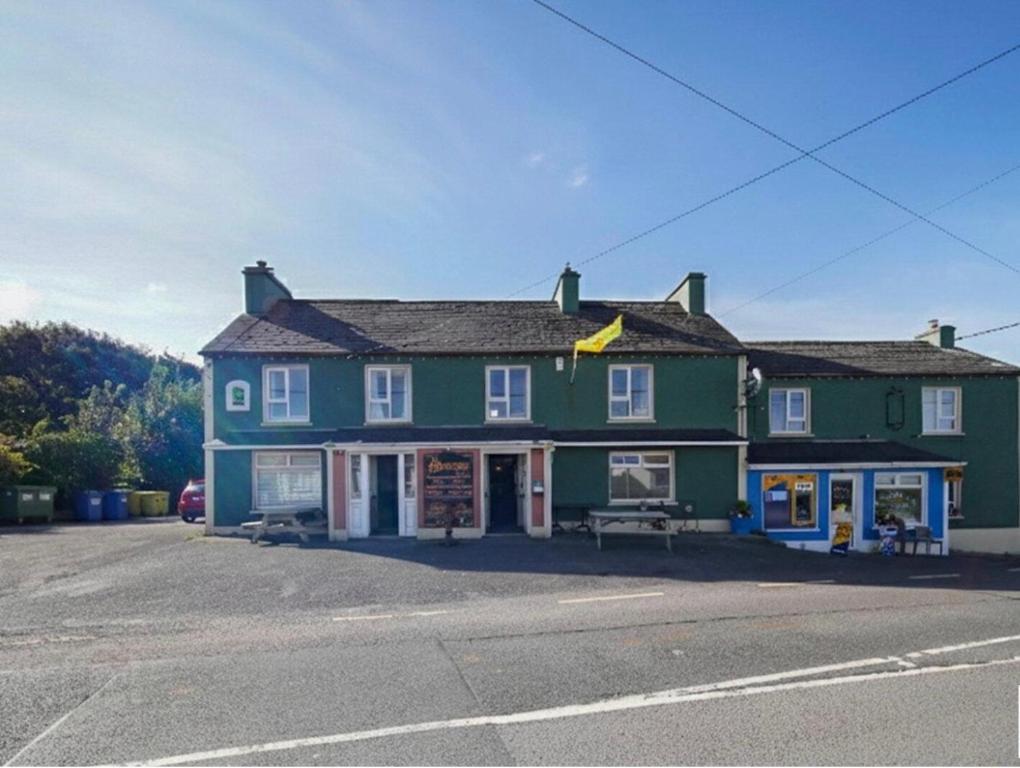 a green building with a bench in front of it at ANNORA Bar & Accommodation in Portnoo