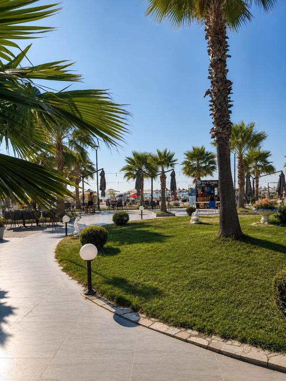 a park with palm trees and a sidewalk at Sole Mare - Beach House in Kavajë