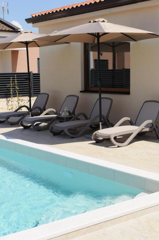 a row of chairs and umbrellas next to a swimming pool at Villa GB in Brtonigla