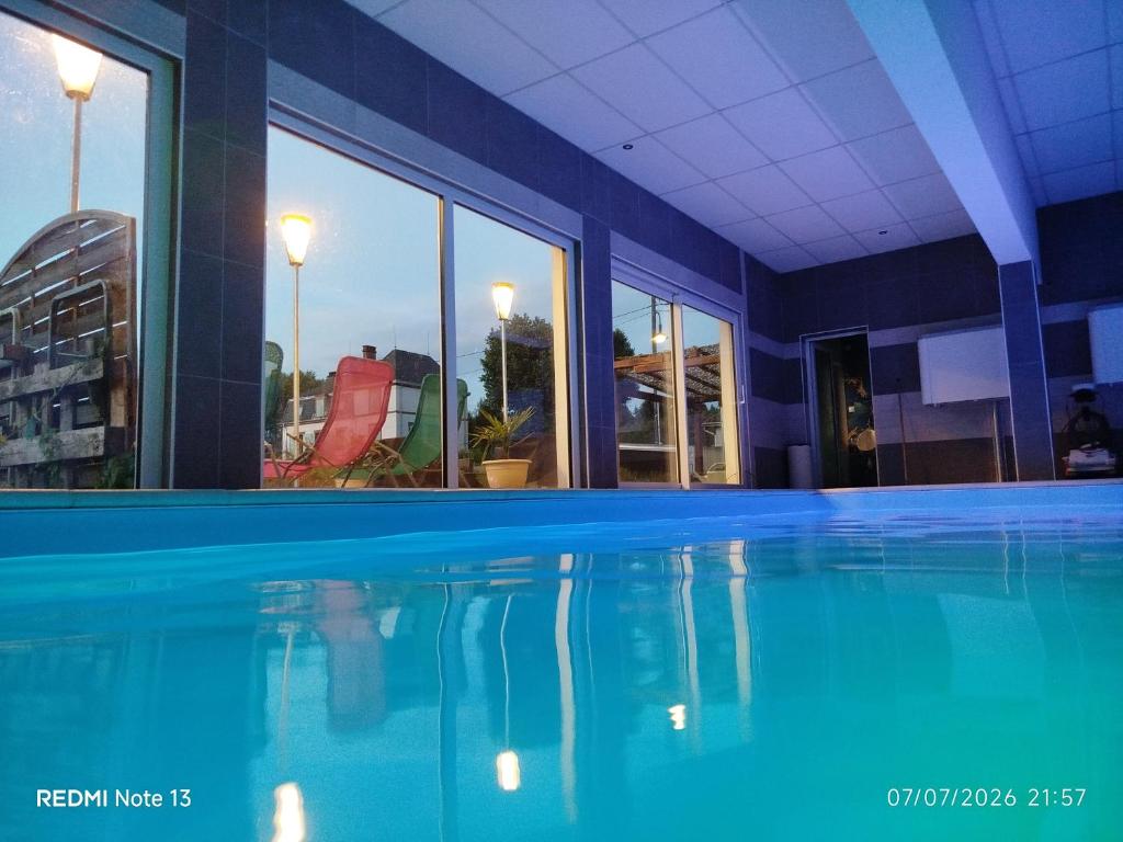 a swimming pool with blue water in a building at Gîte "fils et cotons" Piscine Intérieure chauffée à l'année et sauna in Celles-sur-Plaine