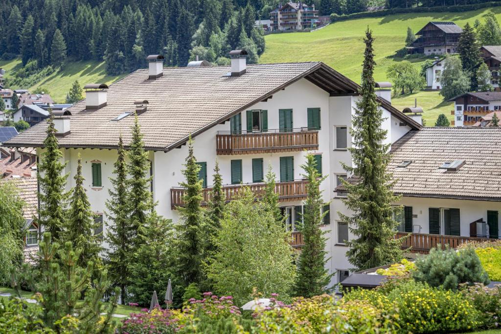 a house in the mountains with trees at Tito Apartments in Ortisei