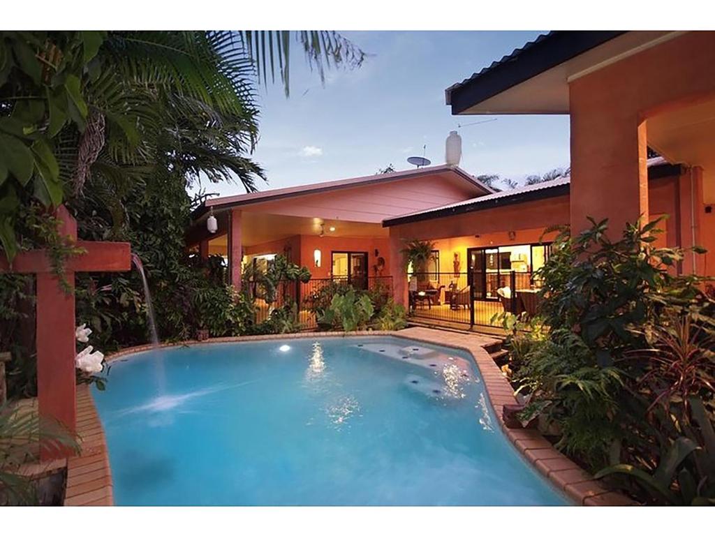 a swimming pool in front of a house at Hacienda Cooya Beach in Mossman