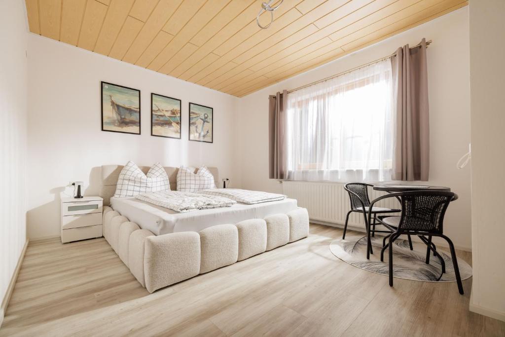 a white bedroom with a bed and a table at Ferienwohnung Leibnitz Südsteiermark in Leibnitz
