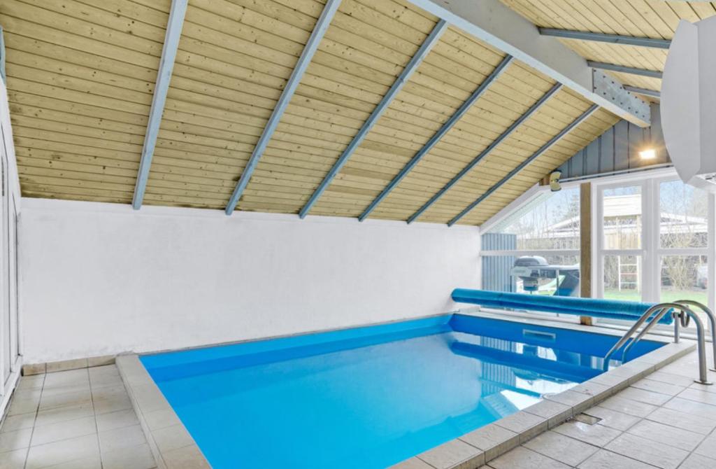 a swimming pool with blue water in a building at Sønderborg Wellness Villa in Skovbyballe