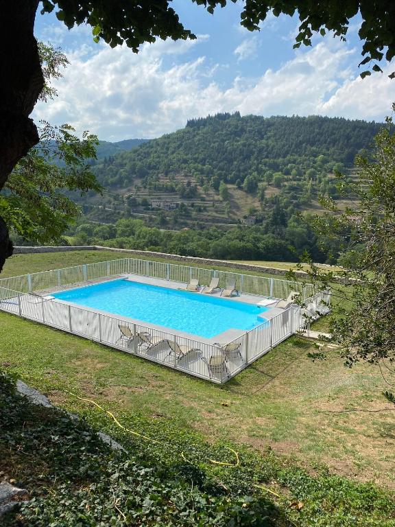 a large swimming pool with chairs on a hill at Manoir majestueux à Satillieu avec piscine privée in Satillieu
