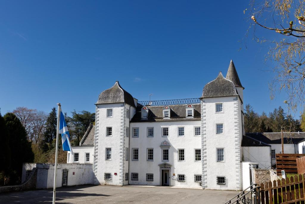 a large white castle with a flag in front of it at Barony Castle Hotel in Peebles