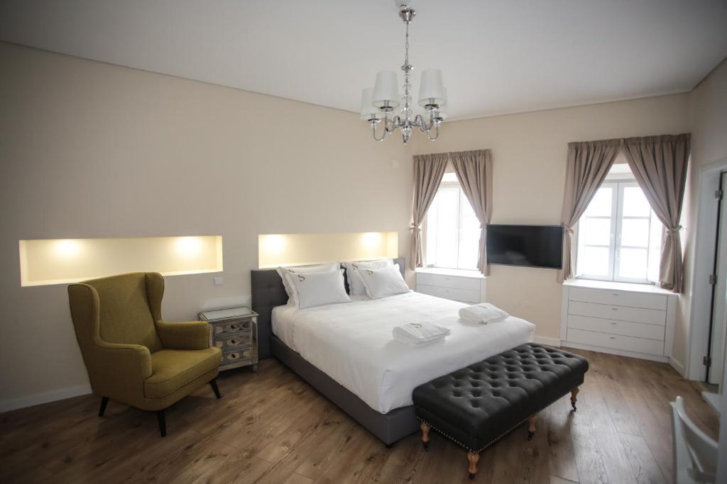 a bedroom with a bed and a chair and a chandelier at Suites Guest House in Cascais