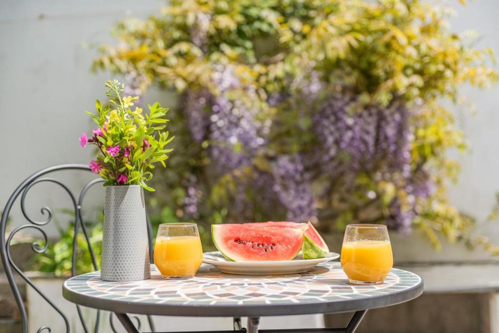 a table with a plate of watermelon and two glasses of orange juice at 1 Bed in Appledore oc-captv in Appledore