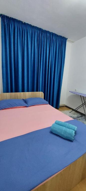 two beds in a room with a blue curtain at Арай 2 - 116 in Qyzylorda