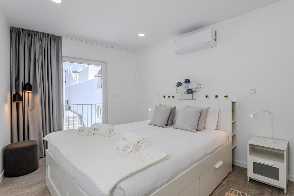 a white bedroom with a large white bed and a window at GuestReady - Sea Apartments in São Roque