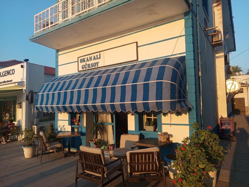a restaurant with a blue and white awning on a building at Okan Ali Gürsoy Otel in Ayvalık