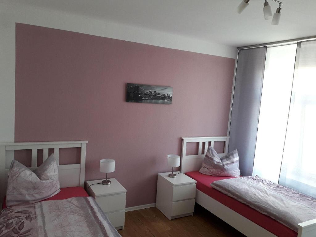 two beds in a room with pink walls at Specht-Ferienwohnung-1-Tangermuende in Tangermünde