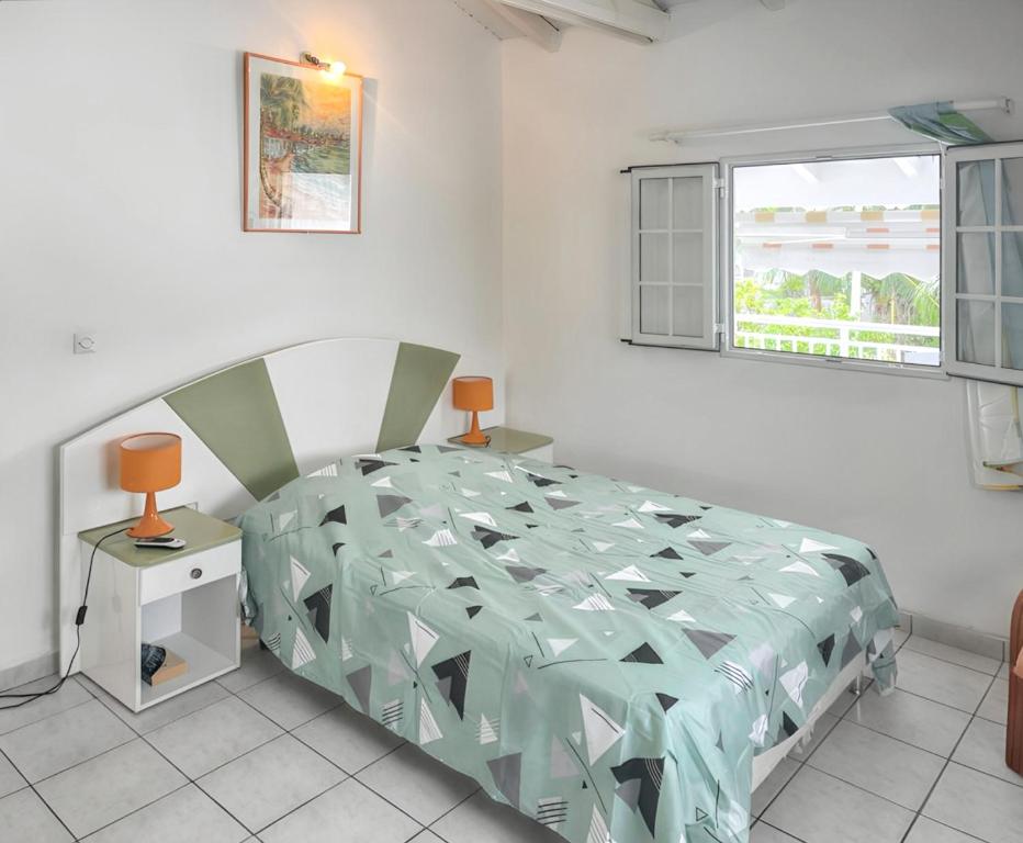 a bedroom with a bed and a window at Appartement convivial au Moule avec jardin clôturé in Le Moule