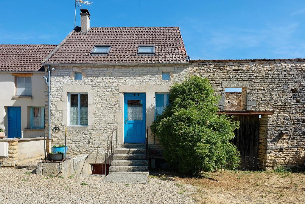 a brick house with a blue door and a bush at Chez Pauline in Massangis