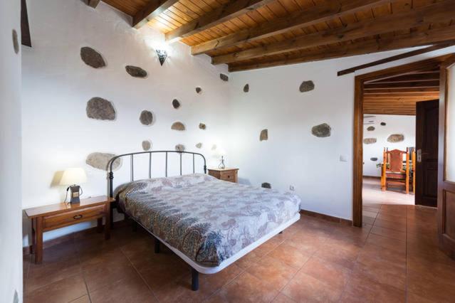 ein Schlafzimmer mit einem Bett und einer Wand mit Steinen in der Unterkunft Country House Lomito De Taidia in Risco Blanco