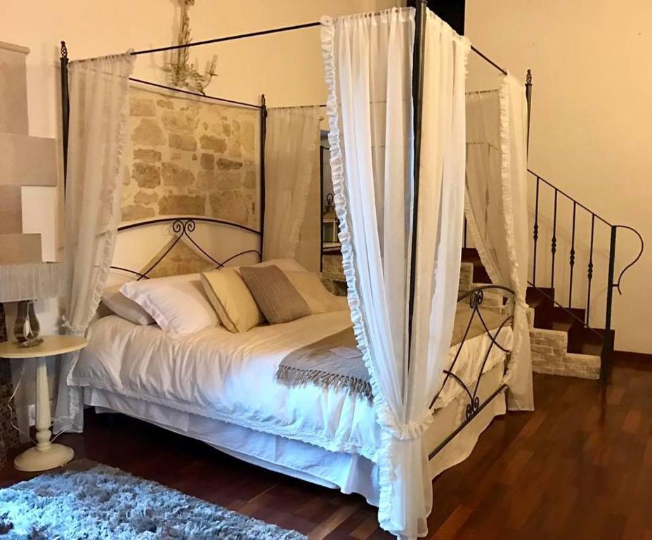a bedroom with a canopy bed with white curtains at Marè Rooms Bari old town center in Bari
