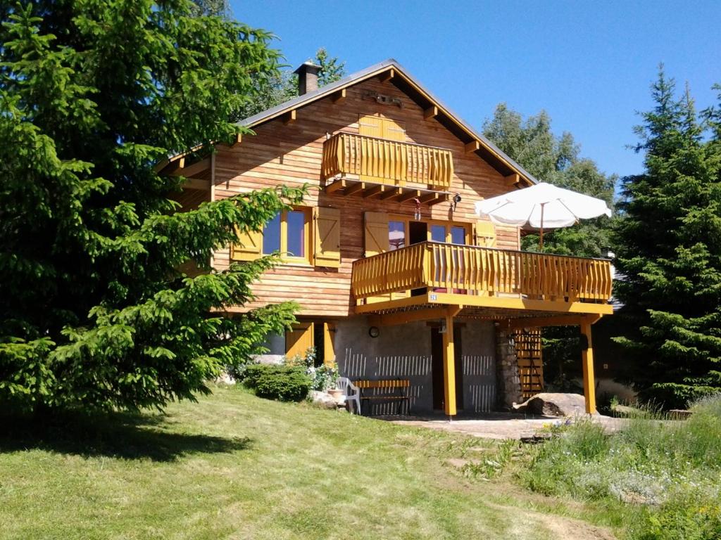 a wooden house with a balcony and an umbrella at Chalet chaleureux à Ax-les-Thermes avec vue sur la montagne in Ax-les-Thermes
