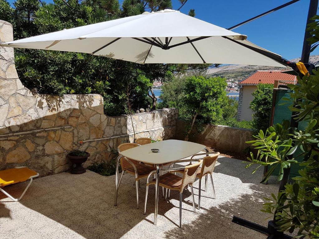 a table and chairs under a white umbrella at Modern apartment with sea view in Pag, 40 sqm in Pag