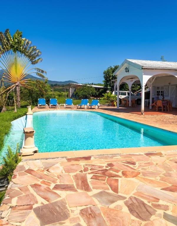 a swimming pool with chairs and a house at Villa Enchantée avec Vue sur mer et Piscine au Carbet in Le Carbet